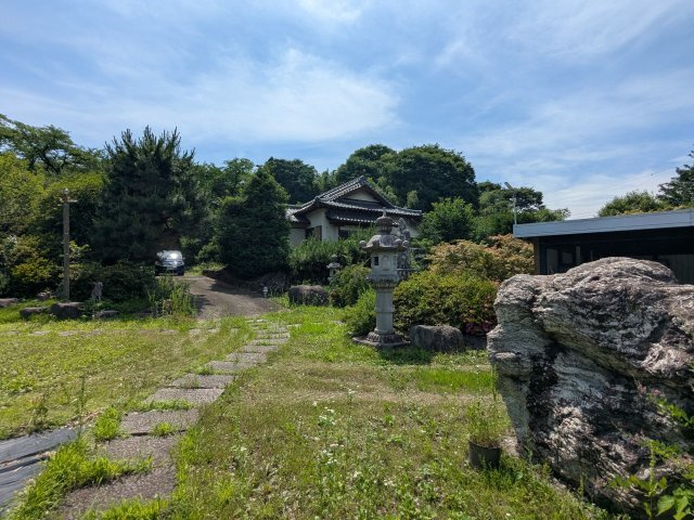 青空と豊かな緑に包まれた解放感あるお庭。石燈籠や巨石が和の趣を深め、心安らぐ空間が広がります。