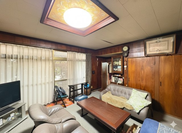 木目調の内装が落ち着いた雰囲気を演出するリビング。大きな掃き出し窓からは自然光が入り、日中は明るく心地よい空間です。ソファを配置してもゆとりがあり、家族団らんや来客時にも対応しやすい広さ。