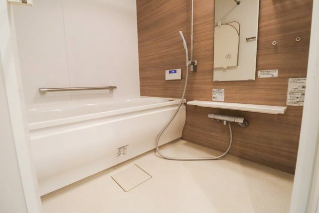 木目調のアクセントパネルが落ち着いたリラックス空間を演出するバスルーム。手すりも設置されており、ご家族皆様が安心してご入浴いただけます