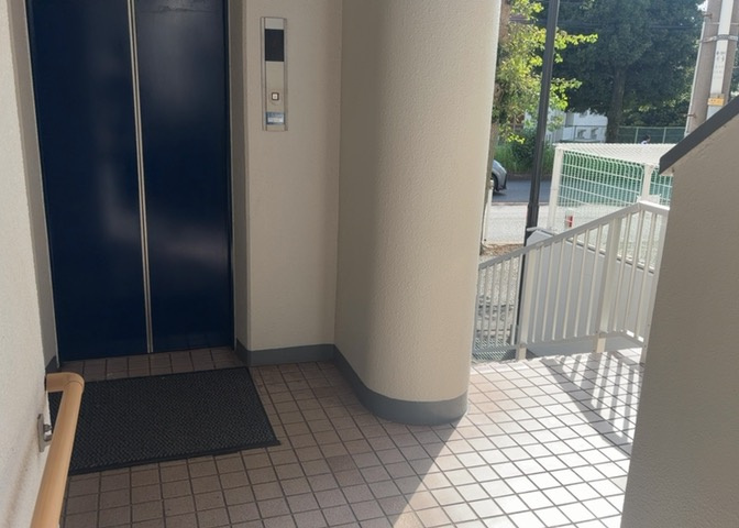 ゆったりとした広さを持つ開放的なロビー空間です。ガラス越しに外の光が差し込み、明るい雰囲気が保たれています。マンションの維持管理状態の良さが伺える、美しく整えられた共有スペースとなっております。