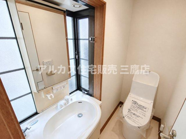 手洗い場と鏡を備えた機能的なトイレ空間。大きな窓があり、明るく解放感のある設計です。