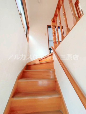 木目を基調とした階段。手すりと窓を備え、住まいの上下階をつなぐ落ち着いた動線です。