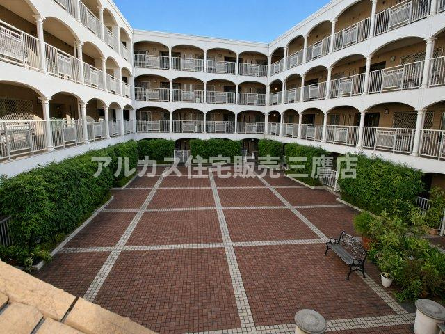 植栽の緑とレンガ敷きの敷地が広がる、開放感あふれる敷地内の中庭（パティオ）。