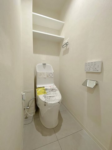 快適にご利用いただける温水洗浄便座付きのトイレ設備へ新規交換済みです。清潔感のある空間に仕上げられており、上部にはトイレットペーパー等を保管できる便利な収納棚も備えています。