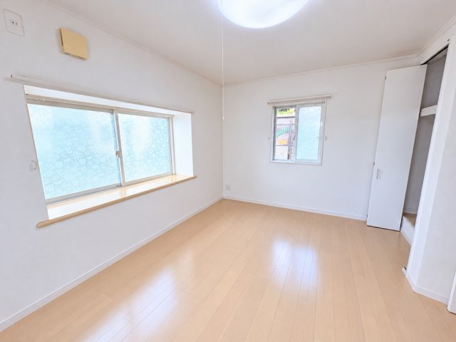 3面に窓を設けた、明るく開放感のある約6.5帖の洋室です。白を基調とした壁面とナチュラルな色合いのフローリングが調和し、すっきりとした住空間を演出しています。日中も心地よく過ごせる点が魅力です。