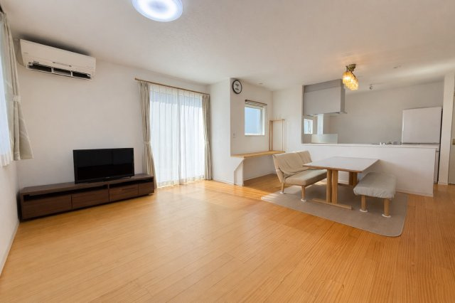 約19.75帖の広々LDKは南側からの自然光が差し込む明るい空間。ナチュラルなフローリングが温かみを演出し、家族がゆったりくつろげます。ダイニングスペースとリビングをゆるやかに分けられるレイアウトです