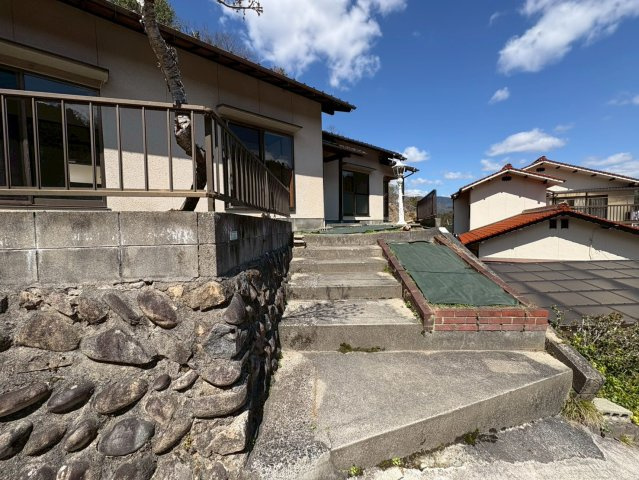 高台に位置する住まいへと続くアプローチ階段になります。段差はしっかり確保されており、安定感のある造りです。住まいへの期待感を高めてくれる導線で、落ち着いた暮らしの始まりを感じられます。