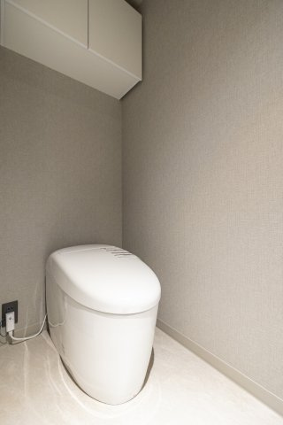 白を基調とした清潔感あふれるトイレ。スッキリとしたデザインで、お手入れのしやすさにも配慮されています。吊戸棚にはストック類を隠して収納でき、限られた空間を機能的かつ美しくお使いいただけます。