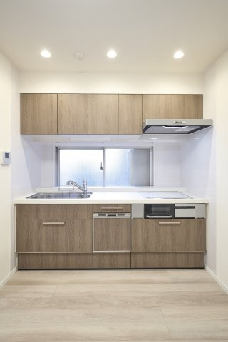 温かみのある木目調のパネルを採用したシステムキッチン。IHクッキングヒーターを備えた機能的な設計で、効率よくお料理を楽しめます。上下に豊富な収納があり、調理器具もすっきりと片付きます。