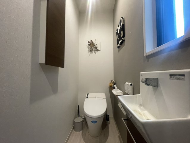 落ち着いた色合いでまとめられた清潔感あるトイレ空間。手洗い器付きで衛生面にも優れ、来客時にも使いやすい仕様。奥行きあるカウンターは小物のディスプレイやストック収納にも便利。温水洗浄便座や節水タイプ！