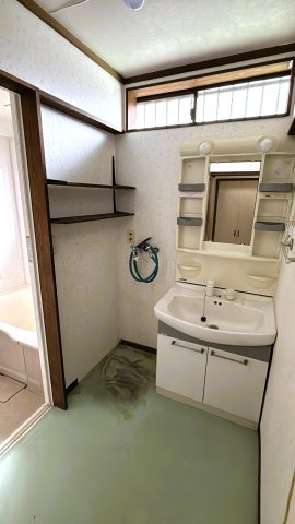 小窓から光が差し込む明るい洗面所。洗剤等を置ける固定棚付き。