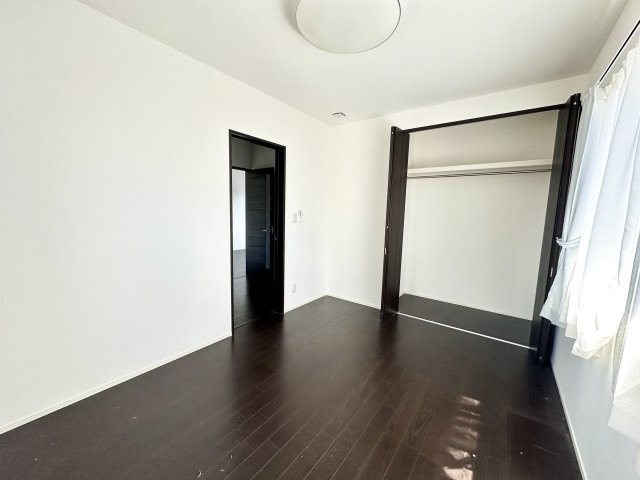 明るい窓からの光が差し込む洋室。ダークブラウンの床と建具が上質な雰囲気を演出し、落ち着いた空間を実現。クローゼットも完備しており、収納力も十分。寝室や書斎、子ども部屋等多目的に活用可能です。