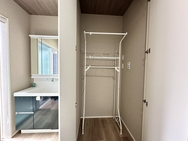 洗面室の一角には便利な収納スペースが設けられており、洗濯カゴやタオル、日用品などをすっきり整理可能。可動式のラックも付いており、使い勝手の良さが魅力で清潔感のある空間です。