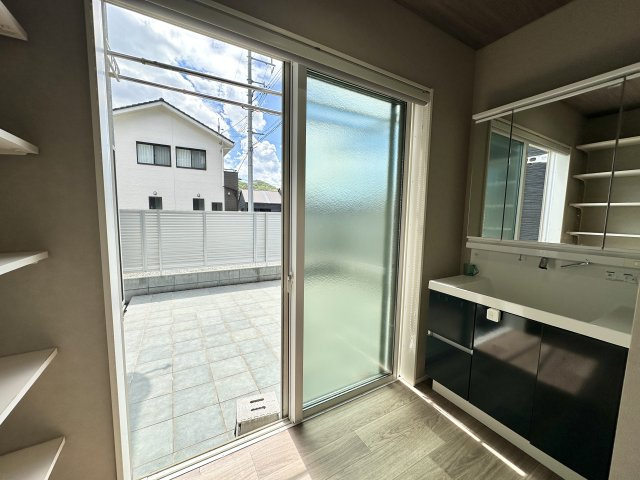 洗面室から直接出入りできるタイル敷きのテラスは、洗濯動線がとてもスムーズで家事効率が良好！南向きの明るい光が差し込み、朝の支度も気持ちよくスタートできます。収納棚もあり、日用品の整理整頓にも便利です。