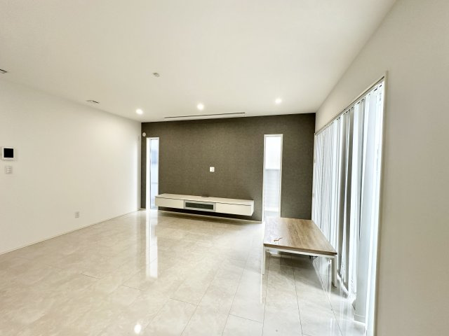 洗練されたデザインの広々としたリビング空間。床には光沢のある大判タイルが使われており、空間が明るく見えます。テレビボード背面のグレートーンの壁が良いアクセントとなっており、空間にメリハリを与えます。