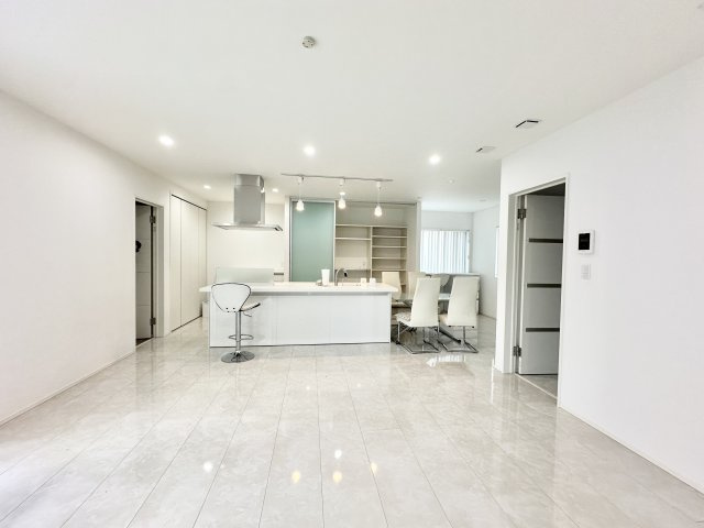 洗練されたデザインの広々としたリビング空間。床には光沢のある大判タイルが使われており、空間が明るく見えます。テレビボード背面のグレートーンの壁が良いアクセントとなっており、空間にメリハリを与えます