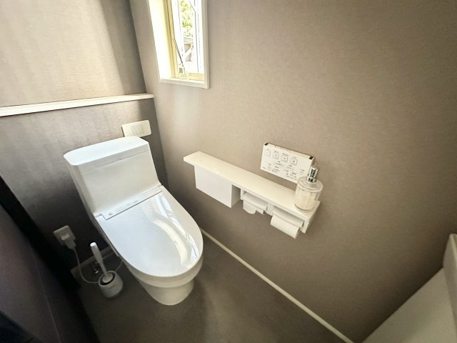 温水洗浄便座トイレはシンプルながらも機能性と清潔感が両立された、非常に快適そうな空間です。壁リモコンタイプの操作パネルで多機能な操作が可能、使いやすさにも配慮されたレイアウトです。