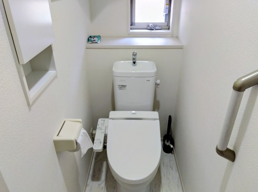 清潔感あふれる白を基調としたトイレです。温水洗浄便座や手すり、小窓付きで快適性と安心感を兼ね備えています。