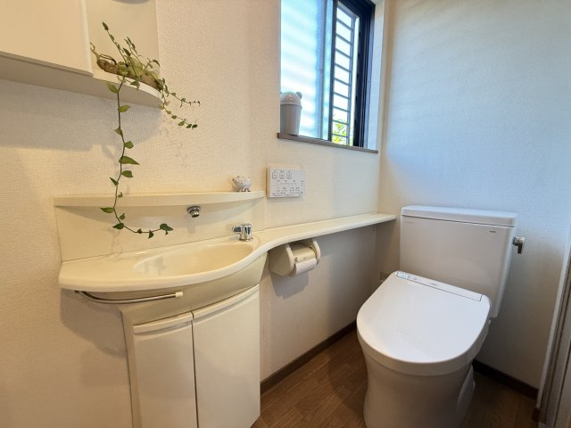 手洗いカウンター付きで、来客時にも使いやすい清潔感あるトイレ空間です。窓があるため自然換気が可能で、明るさも確保されています。空間にゆとりがあり圧迫感を感じにくく、落ち着いて使用できる仕様です。
