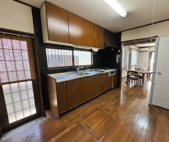 大きな窓から心地よい自然光が差し込む、明るく衛生的なキッチン。隣にはダイニングスペースが広がり、さらに家事室（脱衣所）への動線もスムーズで、忙しい毎日の家事負担を大幅に軽減してくれる機能的な設計です。