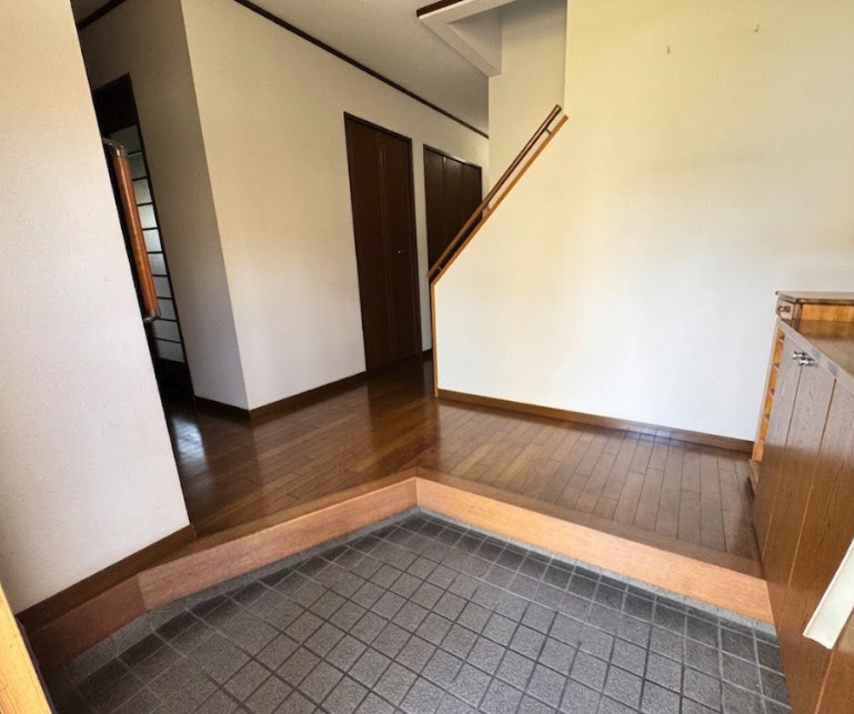 落ち着いた木目調のフローリングと、ダークブラウンの建具がシックな雰囲気を醸し出す、広々とした玄関ホールです。玄関から居住スペースがダイレクトに見えない設計になっており、プライバシーが守られます。