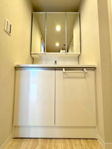 洗面台新規交換　新規交換された洗面化粧台は清潔感があり機能的。洗濯機置場の隣には便利なカウンターを配置し、アイロン掛けやタオル類の整理に役立ちます。動線がスムーズで、毎日快適に身支度が行えます。