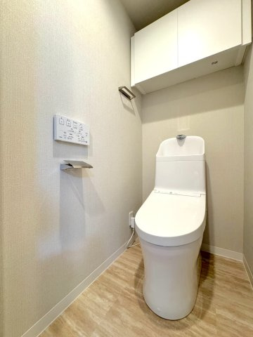 トイレ新規交換　清潔感あふれる温水洗浄便座付きトイレ。上部にはトイレットペーパーや掃除用品などをすっきり収納できる吊戸棚を設置しており、限られた空間をスマートに活用できます。