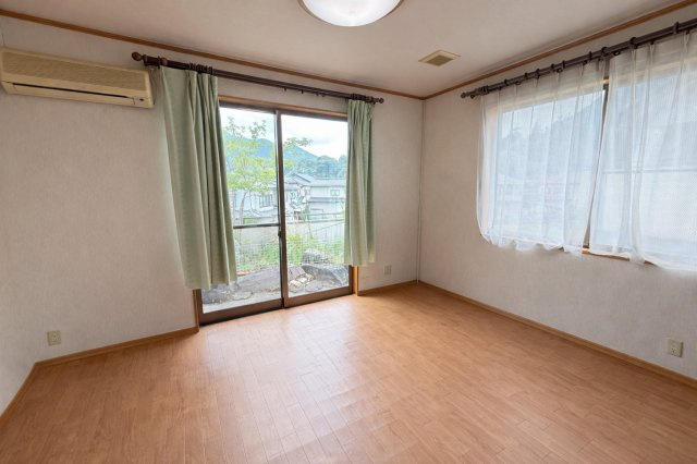 二面採光で明るく風通しの良い洋室です。大きな窓からは庭や周辺の景色を楽しむことができ、心地よい自然光が室内を満たします。木目調のフローリングが温かみを添え、寝室や書斎など多目的に活用可能です。