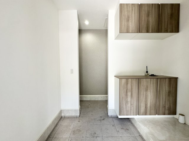 玄関には上下に分かれたシューズボックスを設置し、収納力と見た目のスッキリ感を両立。　天井までの高さを活かした空間設計で、採光も良好。木目調の扉がナチュラルで落ち着いた印象を与えます。