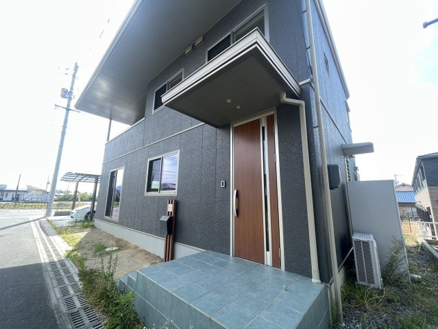 玄関ポーチは屋根付きで、雨の日でも濡れずに出入りできる安心のスペースです。落ち着いた色合いの外壁と木目調のドアが上品な雰囲気を演出。来客時の印象も良く、日常の使いやすさも兼ね備えた玄関まわりです。