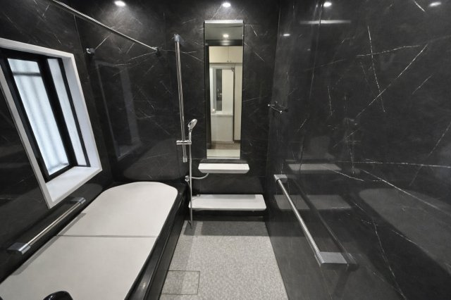 ブラックを基調とした高級感あふれる浴室は、落ち着いた空間で一日の疲れをゆったりと癒せます。手すり付きで安心感もあり、窓からの換気も可能。機能性とデザイン性を兼ね備えた快適なバスルームです。