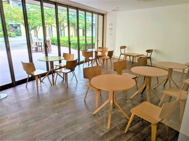 緑に囲まれた開放的な「さくらテラス」。テーブルとチェアが配置され、屋外でゆったりと過ごせる心地よい共用空間です。