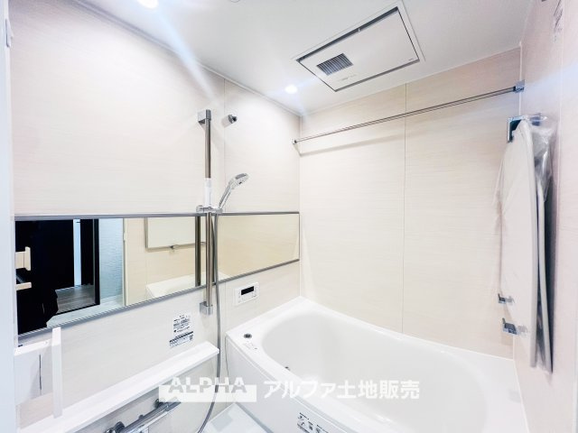 木目調パネルが落ち着いた雰囲気を演出するバスルーム。広々とした浴槽と清潔感のあるデザインで、一日の疲れを癒す快適なリラックス空間を提供します。