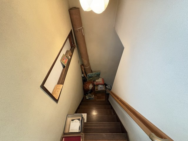 木製の階段は手すり付きで安全性に配慮されており、ご高齢の方や小さなお子様でも安心して上り下りできます。シンプルな壁面は装飾やアレンジも楽しめる余地があり、家族の写真や絵を飾れば温かみのある雰囲気に。