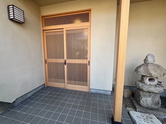 美しい格子戸が主役の和風玄関です。木の温もりを活かした落ち着きある佇まいで、ピカピカした派手さを抑えた上質な質感が魅力。灯篭を添えた坪庭風の演出が、毎日の帰宅時に心癒やす贅沢な空間を創り出します。