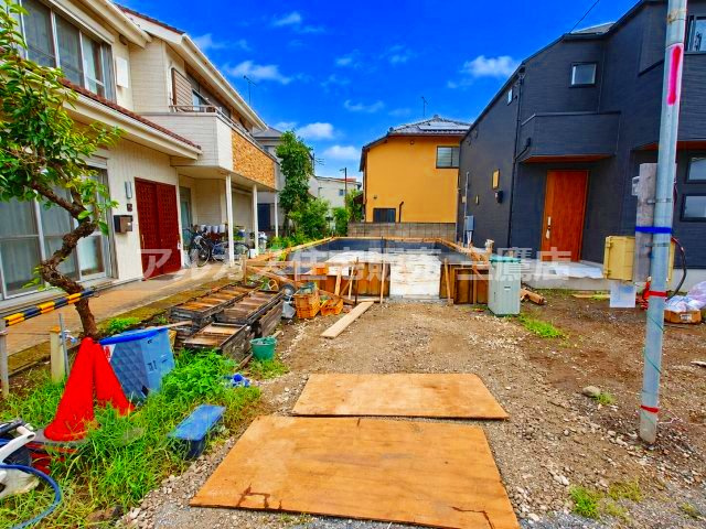基礎工事が進行中の建築現場写真。隣地との間隔や奥行き感が把握しやすく、完成後の住まいをイメージしやすい現地様子です。
