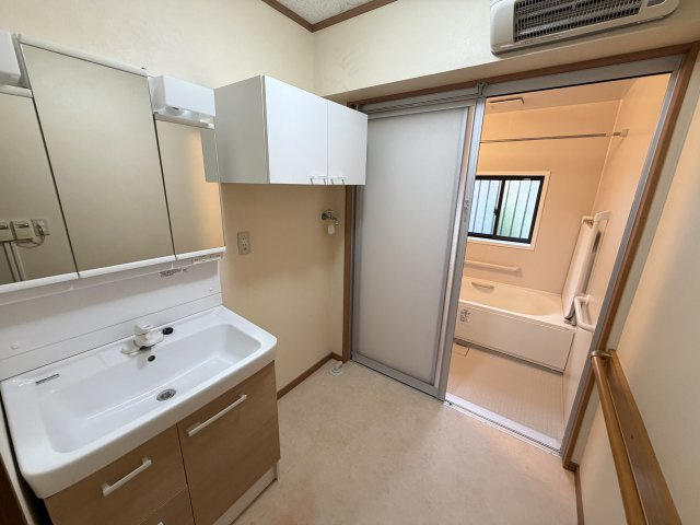 【綺麗で機能的な洗面空間】収納豊富な三面鏡タイプの洗面台と、上部吊戸棚でスッキリ片付く脱衣所です。暖房機器も設置されており、季節を問わず快適に身支度や入浴が楽しめます