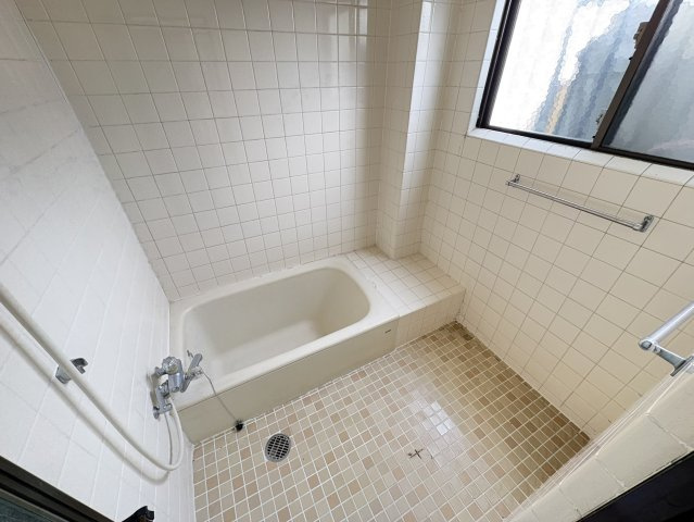 白を基調としたタイル張りの浴室は清潔感があり、ゆったりとした浴槽で一日の疲れをしっかり癒せます。窓付きのため自然換気が可能で、湿気がこもりにくいのも嬉しいポイント。洗い場スペースも広く確保されてます。
