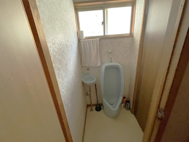 小窓が設けられた明るい小型のトイレスペースで、自然光と換気が確保されている点が魅力です。現状は男性用トイレとしての造りですが、リフォームで洋式トイレや収納を追加することで、より快適な空間になります。