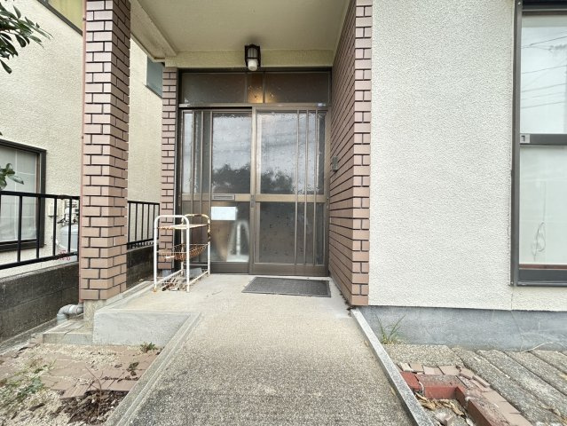 屋根のある玄関ポーチは、雨の日にも出入りしやすい造りです。玄関前にはゆとりのあるスペースが確保され、落ち着いた印象のアプローチとなっています。どこか懐かしさと温かみを感じられる住まいの玄関まわりです。