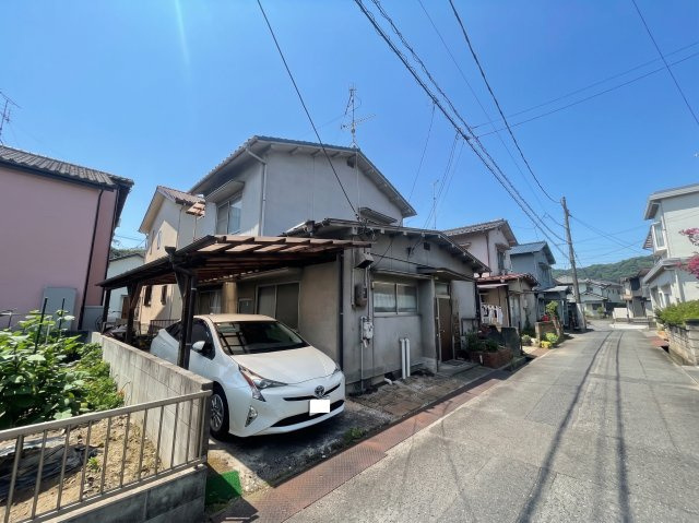 落ち着いた住宅街に建つ住宅です。建物前には駐車スペースがあり、写真では屋根付きのスペースも確認できます。前面道路から敷地や建物の位置関係を確認しやすく、購入後の生活をイメージする際にも参考になります。
