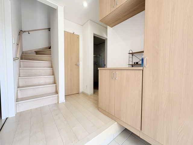 明るい木目調の床と建具が印象的な玄関ホール。シューズボックスを備えており、靴を整理して収納できます。玄関から室内へ入った際の圧迫感が少なく、白を基調とした明るく清潔感のある空間が広がっています。