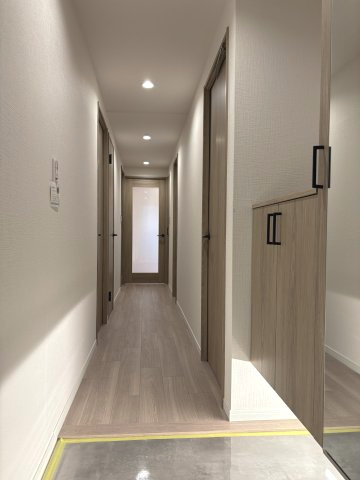 お出かけ前の身だしなみチェックに便利な大型の姿見が付いたシューズボックスを完備。温かみのある木目調の建具としなやかなフローリングがまっすぐ伸び、ダウンライトが奥行きのある美しい廊下を優しく照らします。
