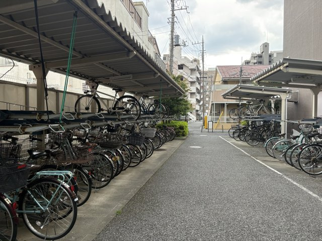 大切な自転車をしっかりと保管できる、屋根付きの敷地内駐輪場です。上下2段式のラックを採用しており、限られたスペースでも整理整頓されています。通路幅にもゆとりがあり、スムーズに出し入れが可能です。