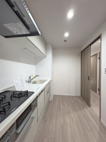 奥に引き戸があり、廊下や他のお部屋への移動もスムーズな2WAY動線タイプのキッチン。背面のスペースにもゆとりがあり、冷蔵庫や家電ラックを配置しても快適に調理作業ができる機能的なレイアウトです。