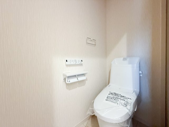 【ベーシアシャワートイレ（LIXIL）】フチレス形状やお掃除リフトアップ機能などお手入れのしやすさが特徴。壁設置型のリモコンと2連紙巻き器が備え付けとなっている超節水タイプ！