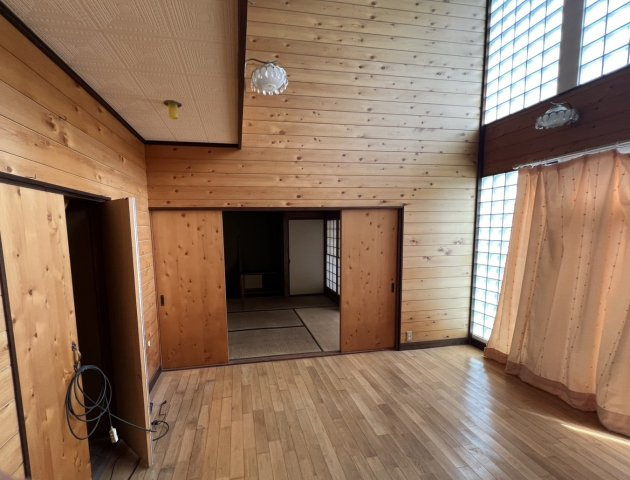 木の温もりを感じられる洋室8帖。高い天井と吹抜によって、帖数以上の開放感を感じられる特徴的な空間です。隣接する和室へ続く動線もあり、和洋それぞれの空間を一体的に活用できます。明るさもポイント。