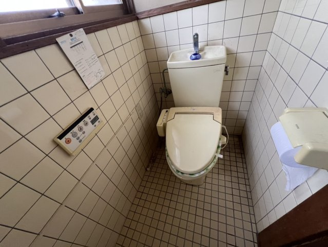 窓を設けたトイレで、自然換気がしやすいのがポイントです。壁や床にはタイルを採用。手洗い付きのタンクで、必要な設備がまとまった空間です。リフォームでお好みの内装へアレンジするのもおすすめです。