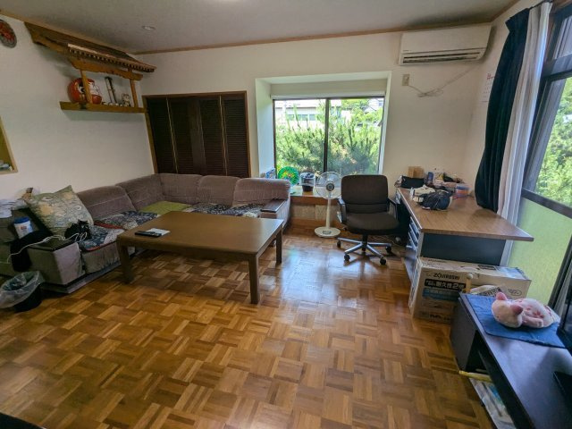 大きな窓から明るい光が差し込む広々とした居間。木目調フロアが温かみのある心地よい空間を演出します。