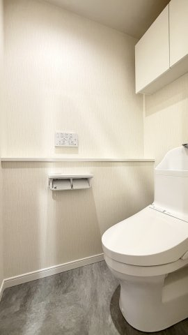 【トイレ】　上部に吊戸棚のある、白を基調とした清潔感のある空間です。トイレは温水洗浄便座付です。